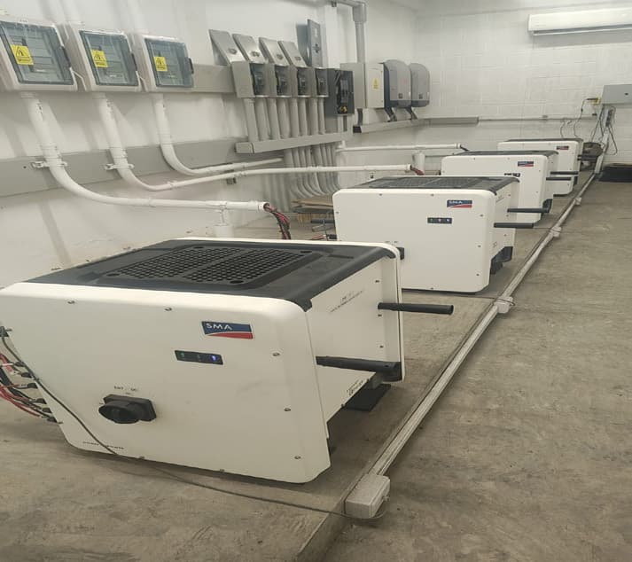 Batería de inversores SMA instalados en muro dentro de una nave industrial.